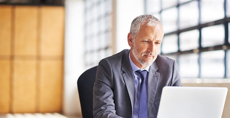 Cropped shot of a mature businessman working on his laptop in the office