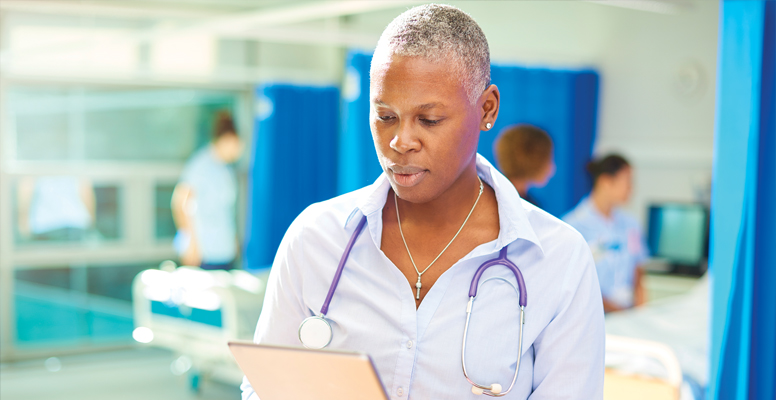 A female doctor checks her digital tablet on a hospital ward 