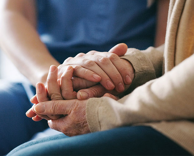 Cropped shot of a senior woman holding hands with a nurse