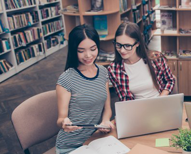 Two young women working together at laptop