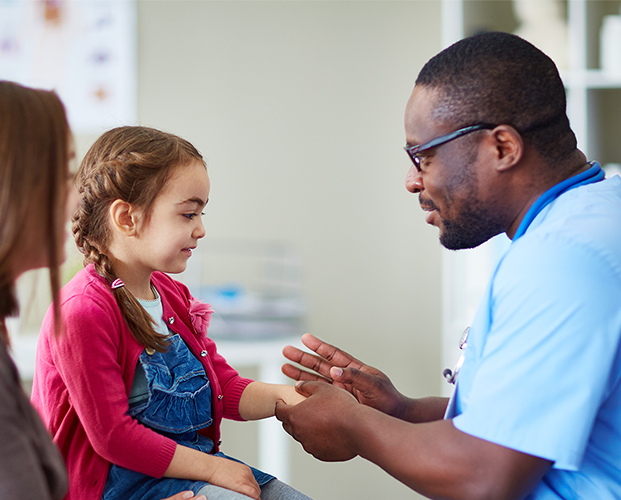 Friendly happy doctor pediatrician with patient child girl in office at clinic