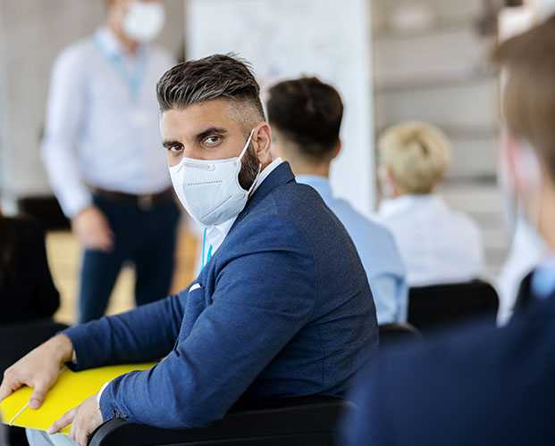Professional man sitting in office wearing mask