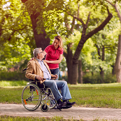 Senior man in wheelchair with happy caregiver daughter