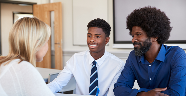 Father And Teenage Son Having Discussion With Female Teacher 