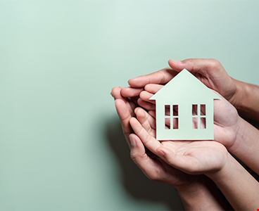 Hands holding wooden house family home