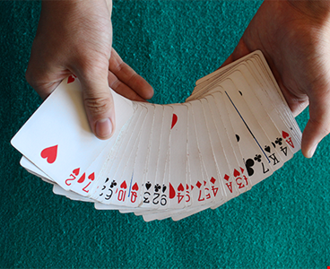 Hands showing cards from a poker deck on green background
