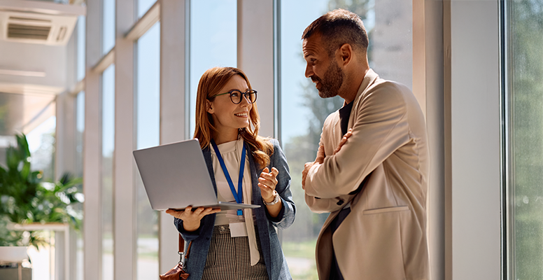 Happy business colleagues communicating while using laptop