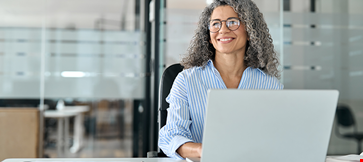Older professional business woman working in office with laptop
