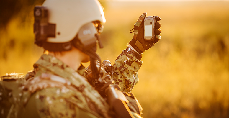 Portrait of young soldier face with GPS device against a sunset background