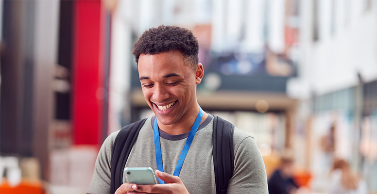 Smiling male college student checking mobile