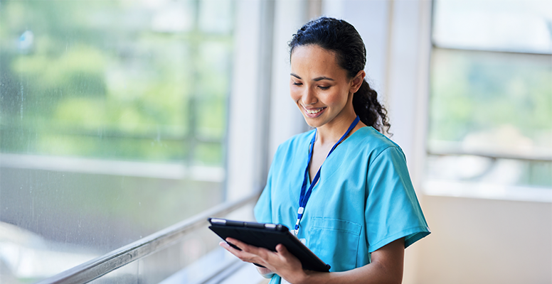 Smiling Nurse in Hospital Scrubs Using Digital Tablet