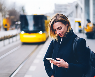 Smiling young woman checking city traffic using smartphone