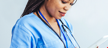 Smiling nurse in scrubs using a digital tablet