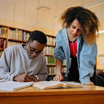 Shot of two university students working together in the library at campus