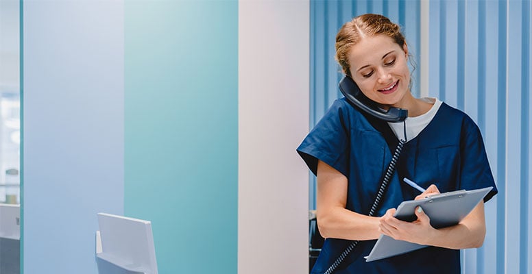 Caucasian female practitioner working at reception desk while answering phone calls