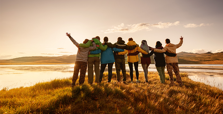 Happy family is standing and hugging together against a lake