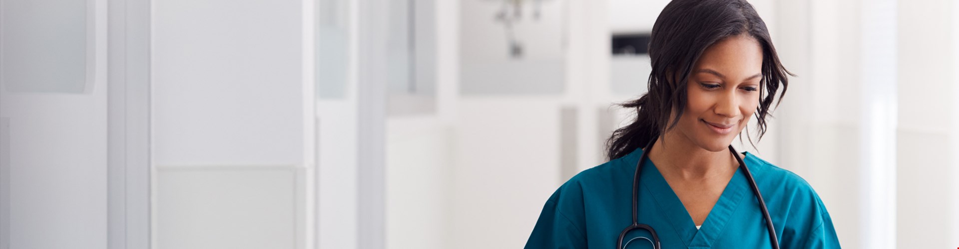 Female doctor wearing scrubs in hospital corridor using digital tablet
