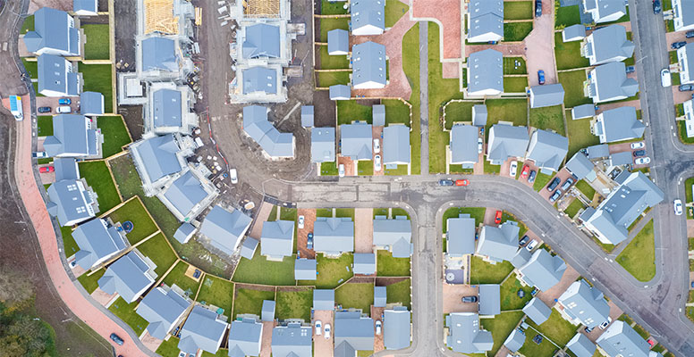 Suburban houses in row aerial view in summer illuminating gardens