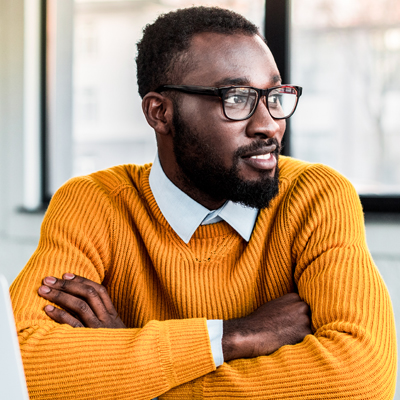 Smiling african american businessman with crossed arms in office