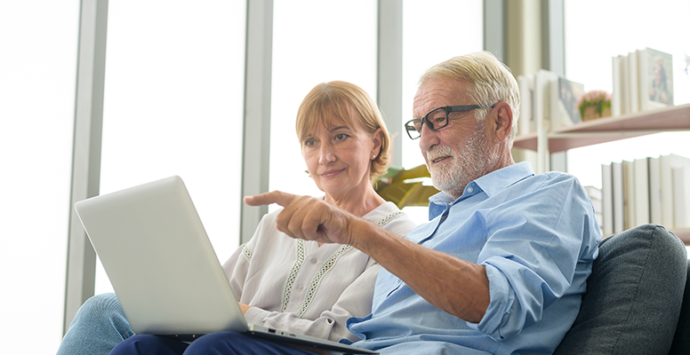 Happy Caucasian senior couple using laptop at home