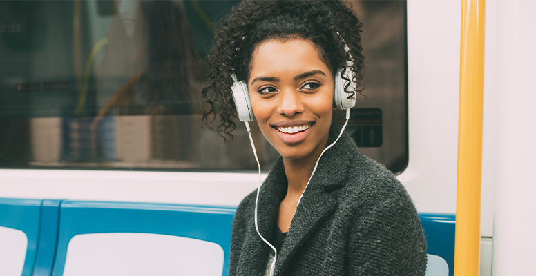 Happy young woman sitting inside the underground listening to music